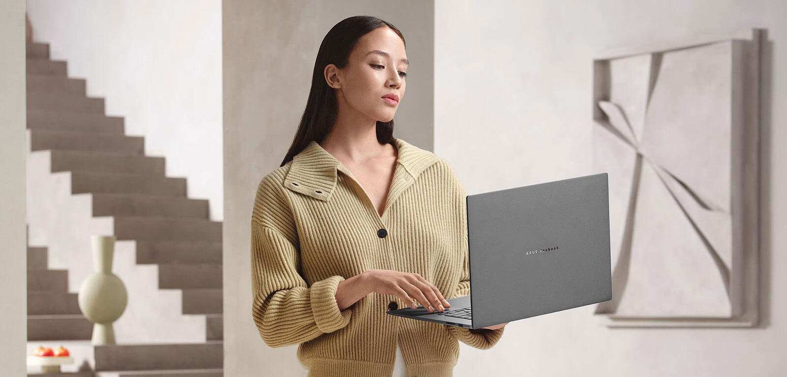 Businesswoman trzyma Zenbook S16 jedną ręką, podkreśla ego lekkość i mobilność.