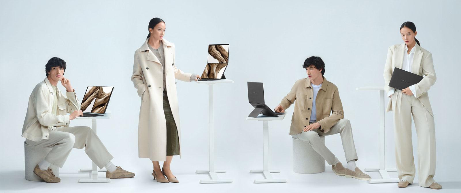 Zdjęcie przedstawia cztery osoby stojące lub siedzące przy stole z laptopami ASUS Zenbook DUO w różnych trybach pracy.